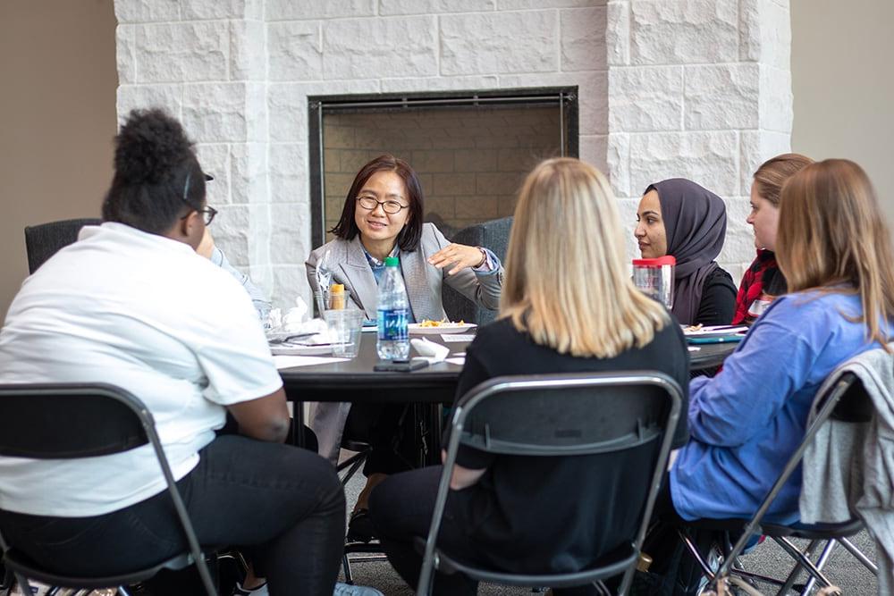 学生 sit around a table during a cultural discussion event